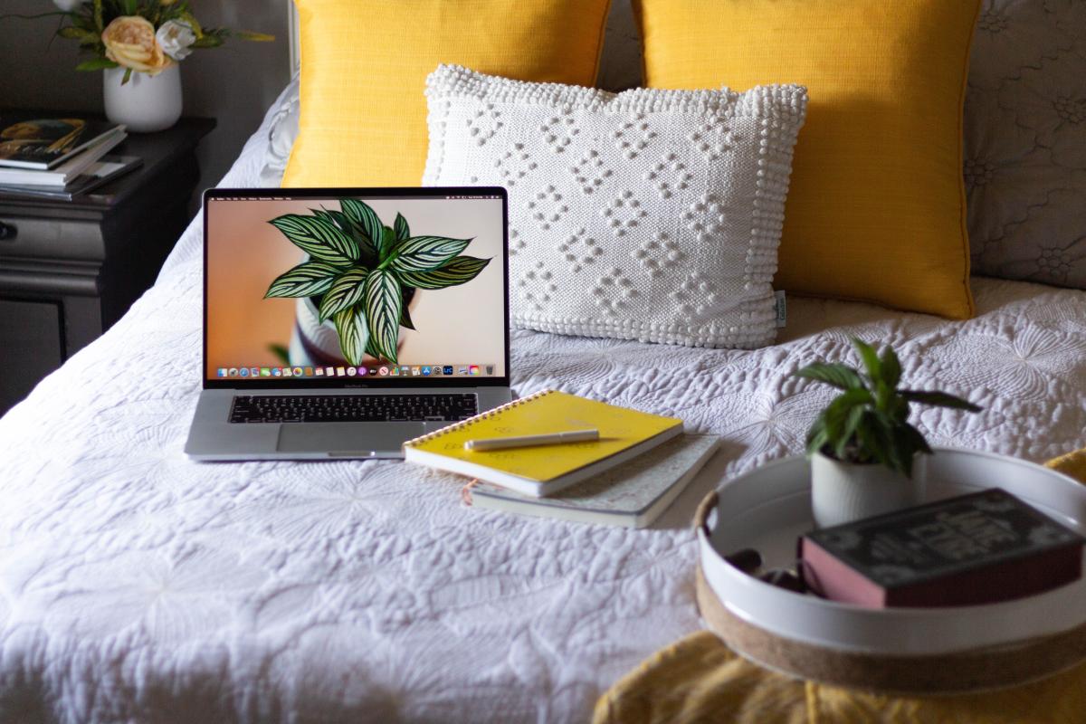 Laptop und Notiznuch auf dem Bett